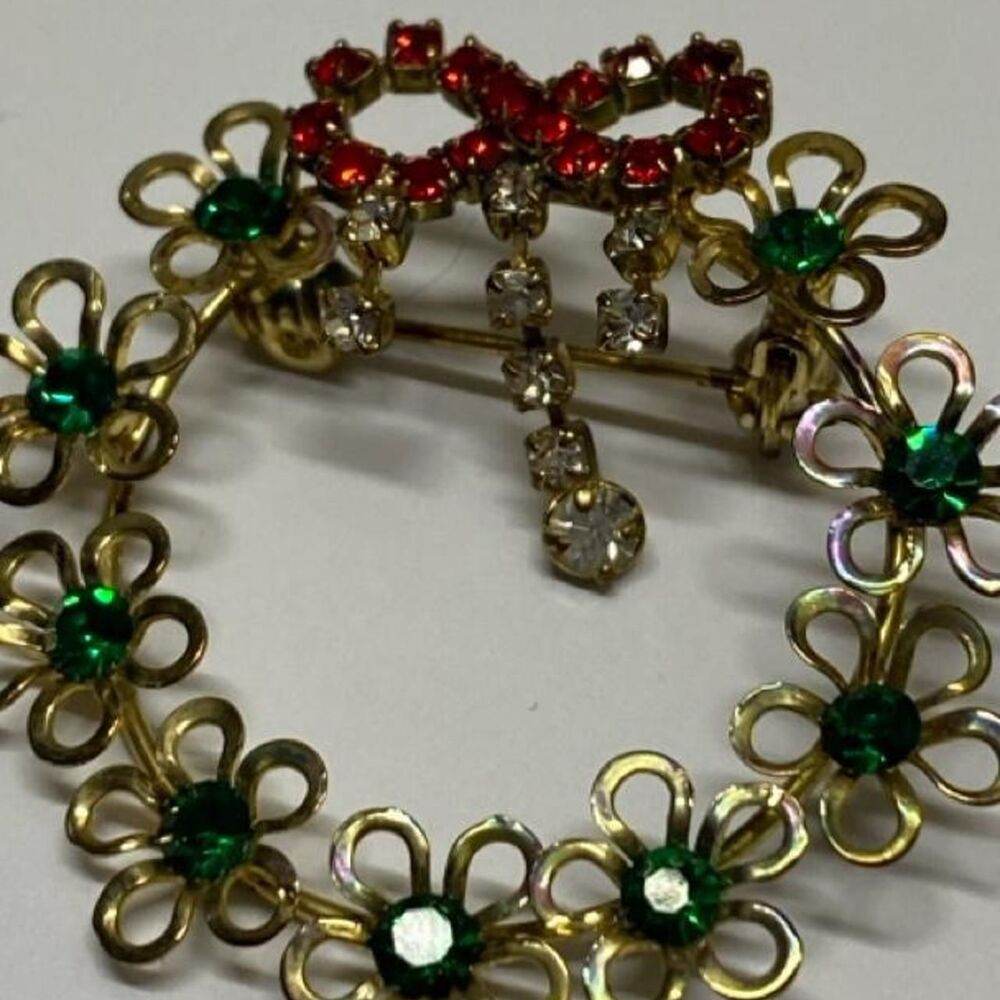 ^gold-tone Christmas wreath brooch decorated with red and green rhinestones 1960